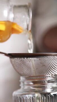 Chef colando alm&iacute;bar de melocot&oacute;n para una receta culinaria moderna. Un chef profesional filtrando alm&iacute;bar casero de melocot&oacute;n con un colador. Conserva artesanal, proceso de gastronom&iacute;a moderna.