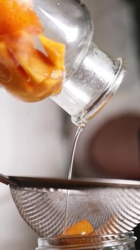 Chef colando alm&iacute;bar de melocot&oacute;n para una receta culinaria moderna. Un chef profesional filtrando alm&iacute;bar casero de melocot&oacute;n con un colador. Conserva artesanal, proceso de gastronom&iacute;a moderna.