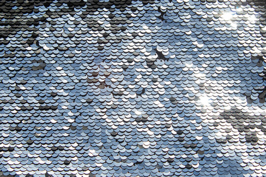 Silver sequin texture with shimmering scale pattern and reflective metallic sparkle surface