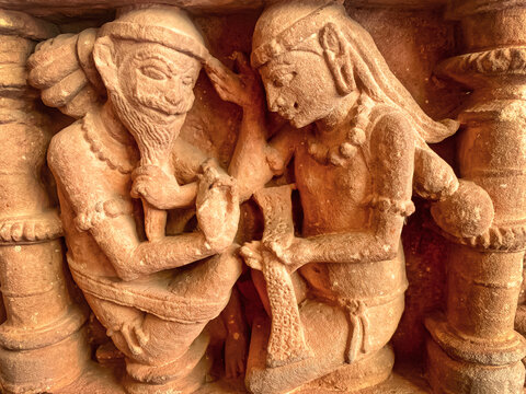 An ancient stone relief depicting Hindu deities. A detailed sculpture depicting Shiva with a third eye and Parvati seated nearby.