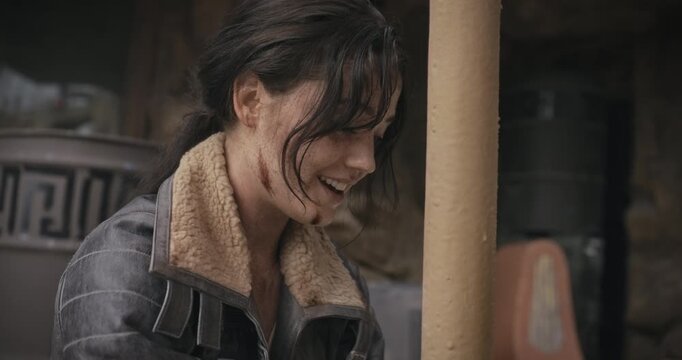 Beat up woman in sci-fi world smiling and talking to someone off screen