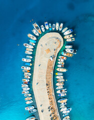 Obraz premium Aerial view of boats and luxury yachts in dock at sunset in summer in Krk island, Croatia. Colorful landscape with sailboats and motorboats in sea bay, jetty, clear blue sea. Top down view of harbor