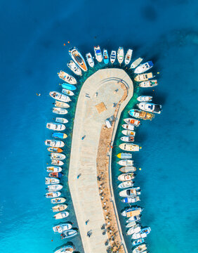 Aerial view of boats and luxury yachts in dock at sunset in summer in Krk island, Croatia. Colorful landscape with sailboats and motorboats in sea bay, jetty, clear blue sea. Top down view of harbor