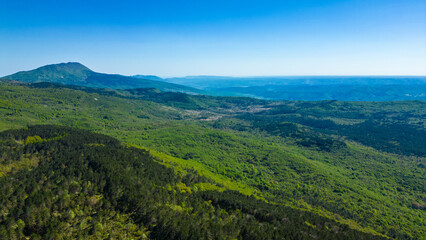 Obraz premium An expansive aerial view of the lush green Ucka mountain range and surrounding forests under a bright, clear spring sky in Istria, Croatia.