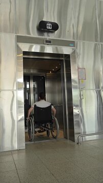 A Caucasian woman in a wheelchair uses an elevator.