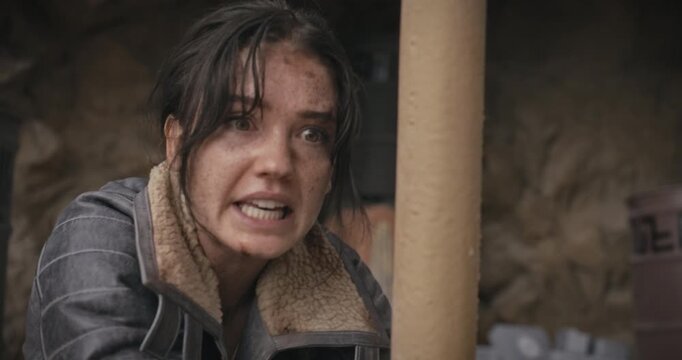 Dirty, bound woman in sci-fi area scolding someone off screen then smirking at them