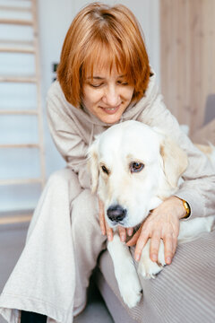 Happy Mature Woman Playing With Golden Retriever In Cozy Tiny House Living Room