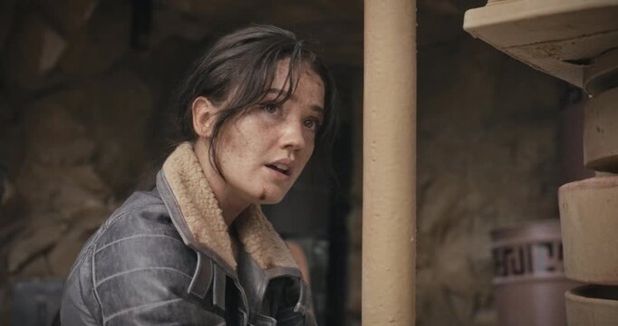 Tired, beat up woman bound to pole in sci-fi area as she looks around