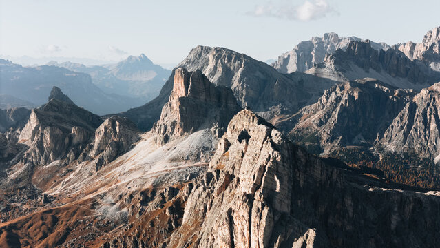 Aerial view of the jagged rocky peaks and steep slopes of Passo Giau in the heart of the Dolomites under a clear sky Colle Santa Lucia, Veneto, Italy.