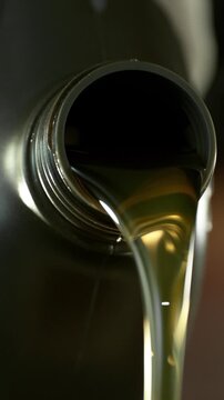 Super slow motion (1000 fps) cinematic shot of motor oil pouring from a container with dynamic camera movement around the bottle neck. Smooth golden liquid flow with bubbles and reflections.