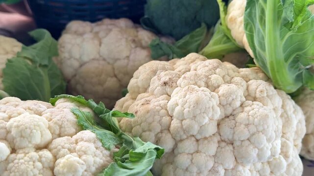 Beautiful white cauliflower heads displayed on bazaar counter with crisp fresh texture and clean natural vegetable atmosphere for healthy seasonal cooking.