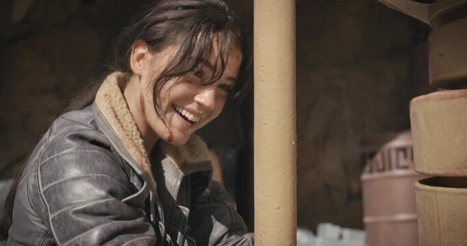 Exhausted, smiley young woman escaping handcuffs in sci-fi area - closeup
