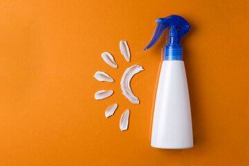 Bottle of sunscreen and texture of cream on colored background top view