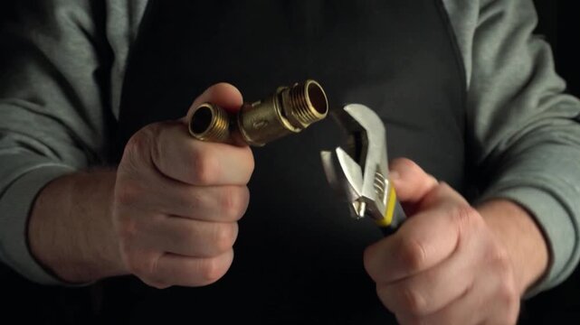 Skilled technician adjusts brass plumbing fittings with adjustable wrench, showcasing precise hand movements in a well-lit workspace