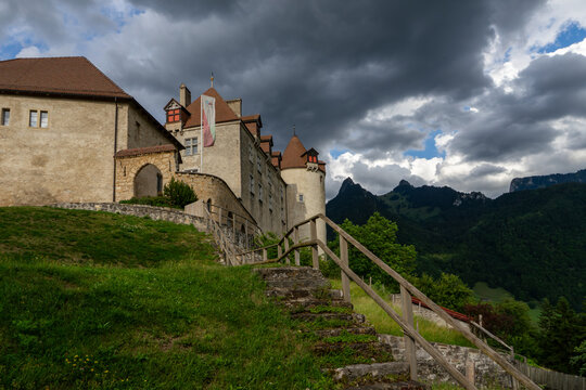 Gruyeres, Switzerland - 14 May 2026: View of the historic Chateau de Gruyeres with its stone walls and towers under a dramatic cloudy sky with mountains in the background.