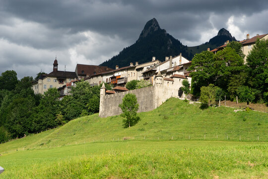 Gruyeres, Switzerland - 14 May 2026: View of the medieval town and castle walls with the Dent de Broc mountain peak under a dramatic cloudy sky.