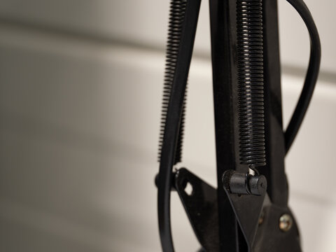 Black tension spring on a desk lamp.