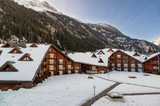 Snow covers the buildings of a resort surrounded by mountains on a winter morning in a picturesque location