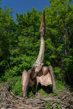 Quetzalcoatlus figurine of a giant prehistoric pterosaur on a nest near the forest.