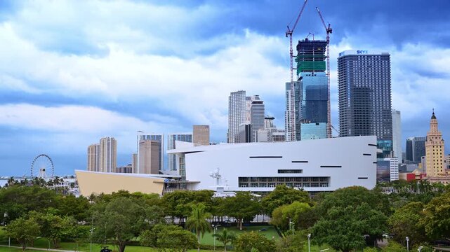 Miami, USA, 16 April 2026: Downtown Miami skyline behind Kaseya Center park. Downtown Miami skyline with Kaseya Center, construction cranes, Freedom Tower and park trees under cloudy sky.