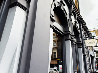 Fototapeta premium Historic gray Rudy's Pizza Napoletana architecture with ornate facade and street reflection in London, UK