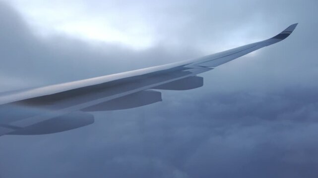 Window view: the airplane activating spoilers while descending slowly through clouds.