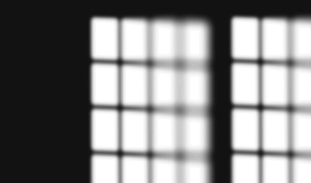 Double window grid shadow pattern cast on dark wall with dark edge