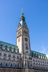 Obraz premium The majestic tower of Hamburg Town Hall rises against a vibrant blue sky, showcasing its neo-Renaissance architecture in Germany's historic city center.
