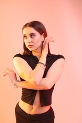Young hip-hop dancer in stylish clothes posing on color background