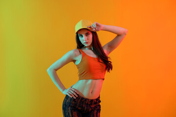 Young hip-hop dancer in stylish clothes posing on color background
