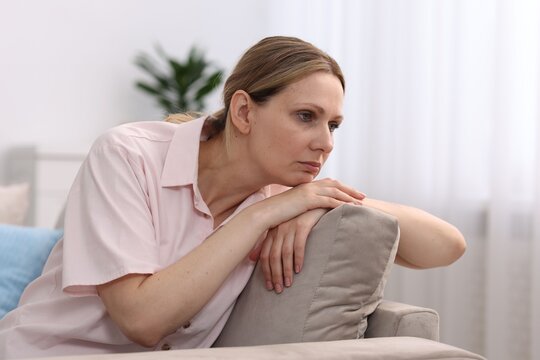 Menopause. Sad woman on sofa at home