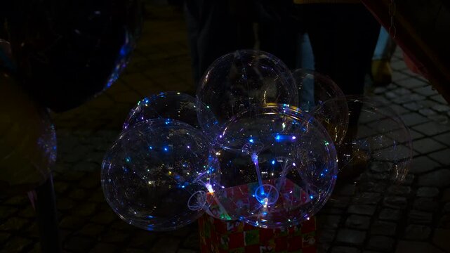 Luminous transparent balloons with led lights glowing at night. Transparent balloons with colorful glowing led light strings inside creating a festive and magical atmosphere in a dark street at night