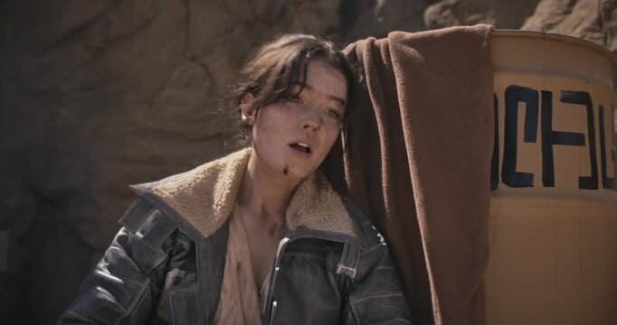 Exhausted, injured female adventurer collapsing near barrel and playing fetch with off-screen animal - medium shot