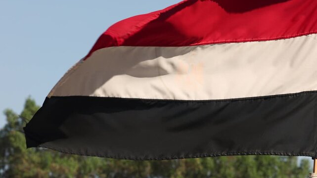 Waving Yemen flag with red white black stripes in bright sunny day