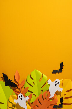 Tropical vertical Halloween paper leaves and ghost decorations with bats on bright orange background