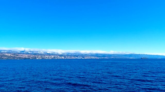 Wide panoramic view of Rijeka city skyline from the Adriatic Sea.Sunny day showcases the harbor, historic buildings, and Kvarner Gulf mountains under a clear blue sky in Primorje-Gorski Kotar, Croatia