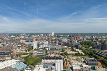 Obraz premium Wide aerial drone view of Leeds city centre in West Yorkshire UK showing the modern skyline high rise buildings and urban development beneath a bright blue sky day in the summer