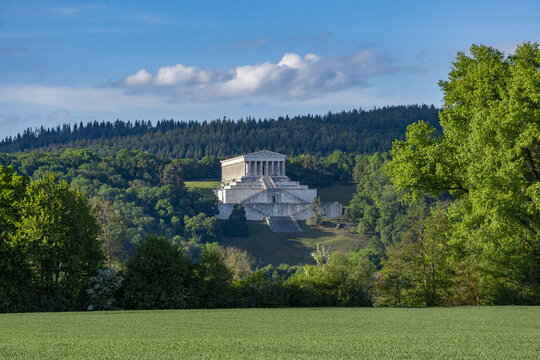 View of the Walhalla memorial featuring neoclassical architecture and marble columns surrounded by lush green trees under a blue sky Donaustauf, Bayern, Germany.