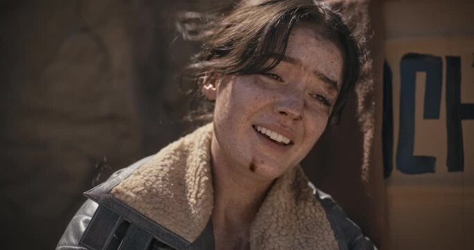 Closeup on exhausted woman in sci-fi world throwing ball for off-screen creature and staring down at old relic