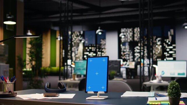 Vertical blue display tablet in contemporary empty office workspace, clean design and comfortable furniture in open space. Stylish corporate environment and modern workplace culture.