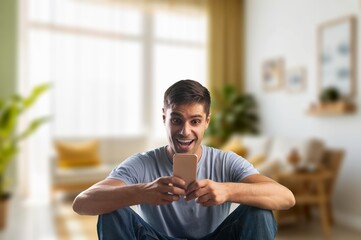 Obraz premium Happy man relaxing holding mobile phone at home