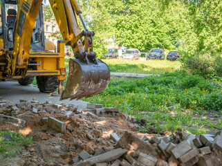Fototapeta premium The photo captures the moment of construction or renovation work, where an excavator dismantles the paving stones on a busy street, creating the impression of progress and transformation.