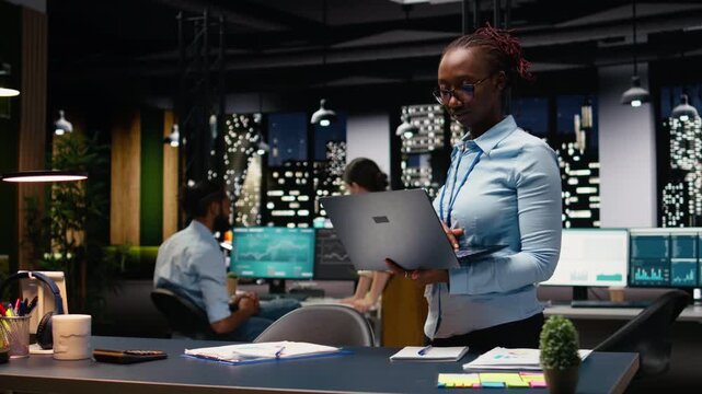 Portrait of african american woman in office managing schedules on laptop, organizing calendar appointments and meetings. Jolly young adult compiling company information records and data.