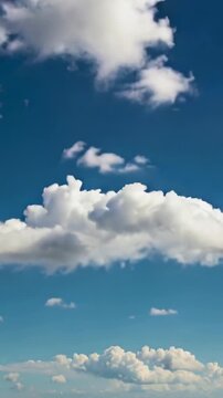 Vertical video: Shifting camera showing large cumulus growing over deep blue sky, smaller cloudlets