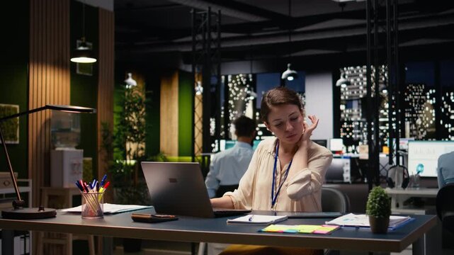 Female accountant in office using laptop, writing down information, working overtime to finish paperwork before deadline. Woman transcribing from device, doing note taking, documenting research.