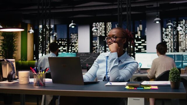 Black manager thinking about new ideas while reviewing notes on laptop, focused yet pensive worker contemplates solutions. Planning strategy to improve performance metrics, business growth.
