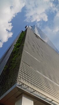 Wide angle dolly camera movement looking up modern office tower business building with blue sky reflections, skyscraper in financial district, architecture and success concept