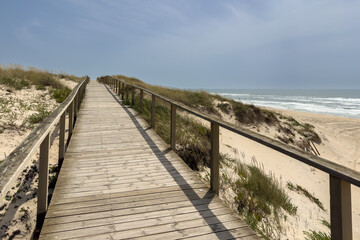 Naklejka premium Wooden Boardwalk Path Rising Over Sandy Ocean Dunes at Praia de Mira Portugal