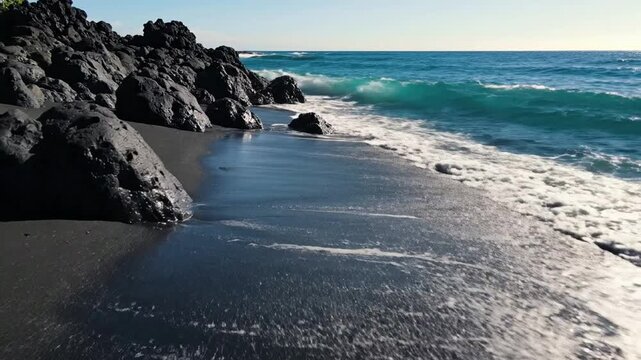 Tropical black sand beach with crashing turquoise waves and volcanic rocks volcanic beach tropical coastline