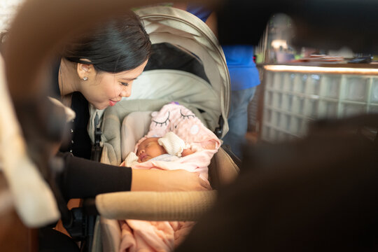 Young Mother Looking Adoringly at Newborn Baby Sleeping in Stroller